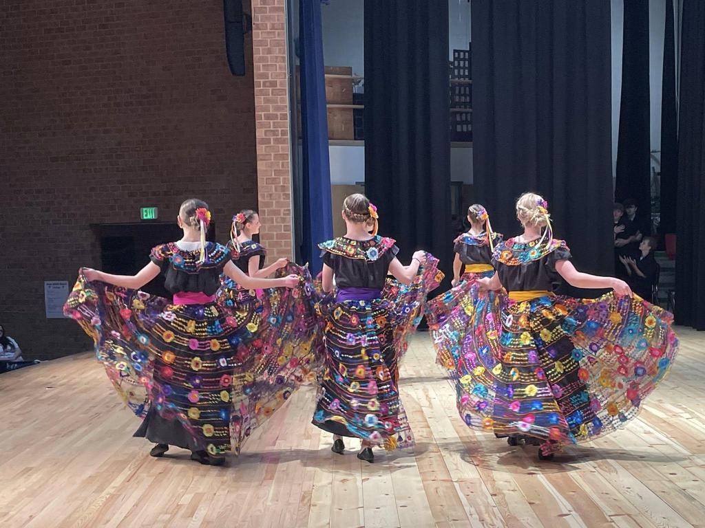 Students dancing in costume on stage